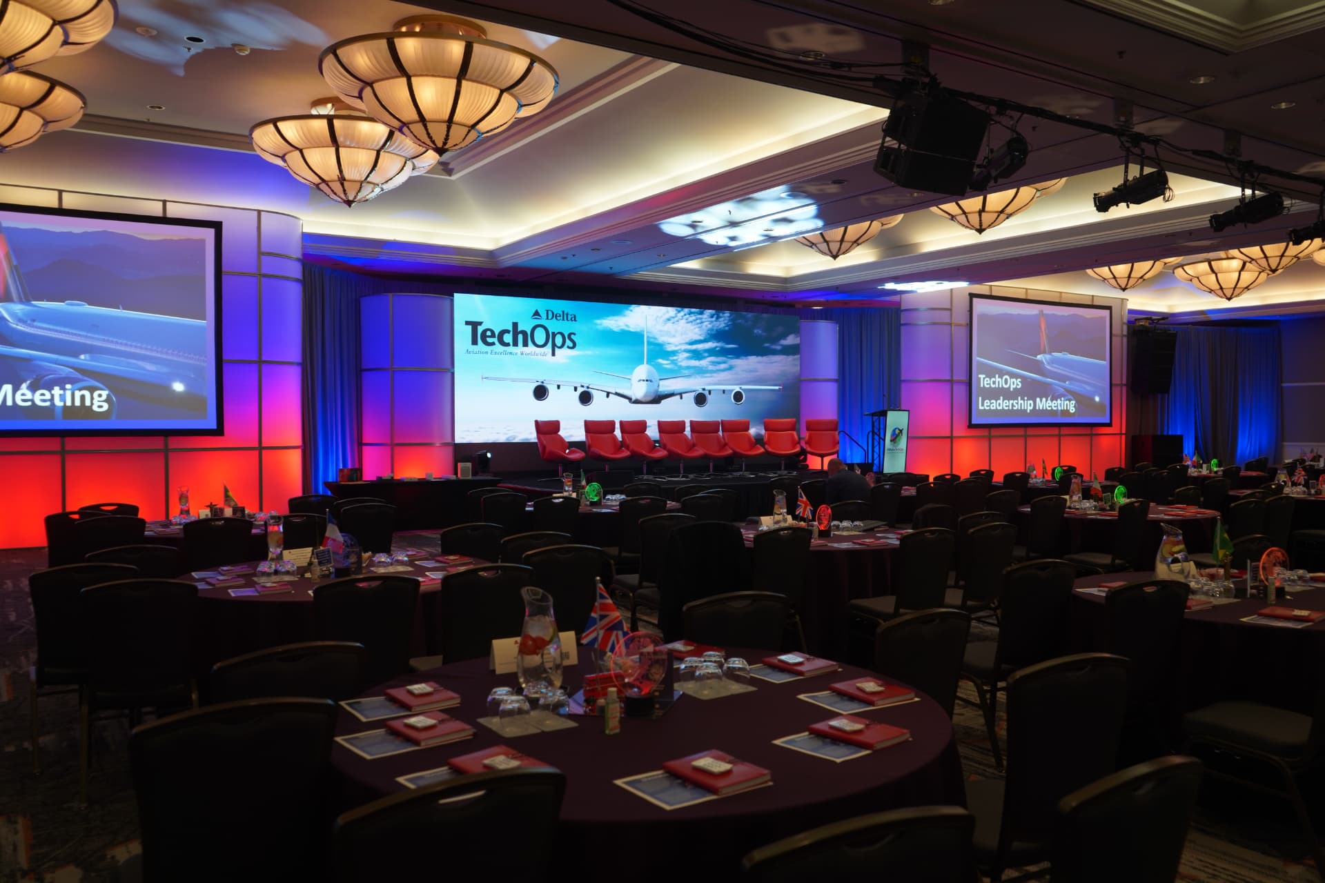Ballroom banquet set with large center screen, side projection screens and red and blue uplighting