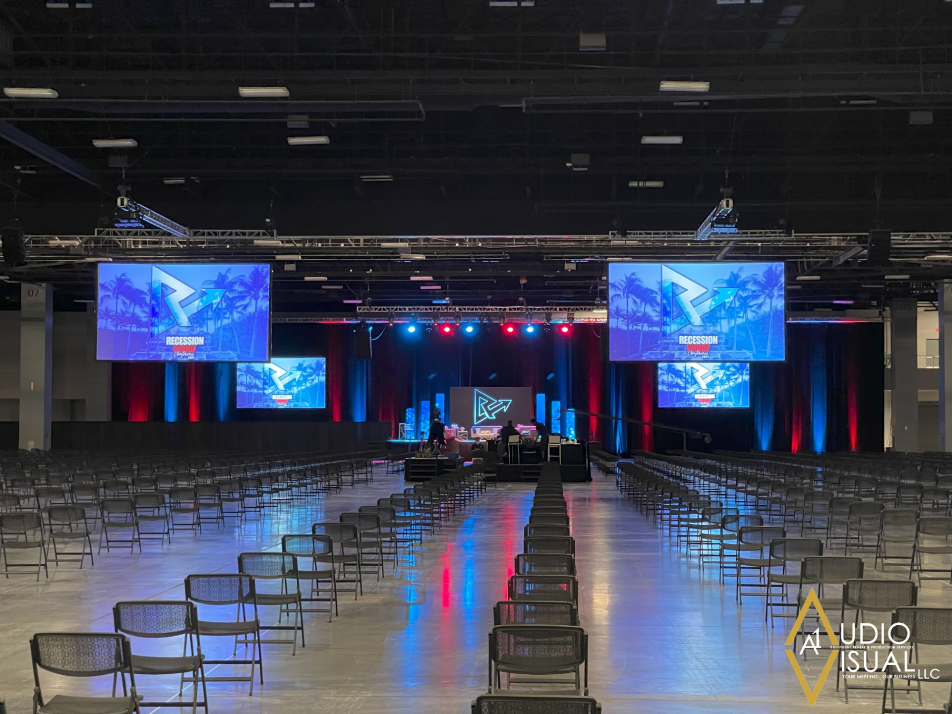 Convention hall conference set with dual projection screens, stage lighting and theater seating